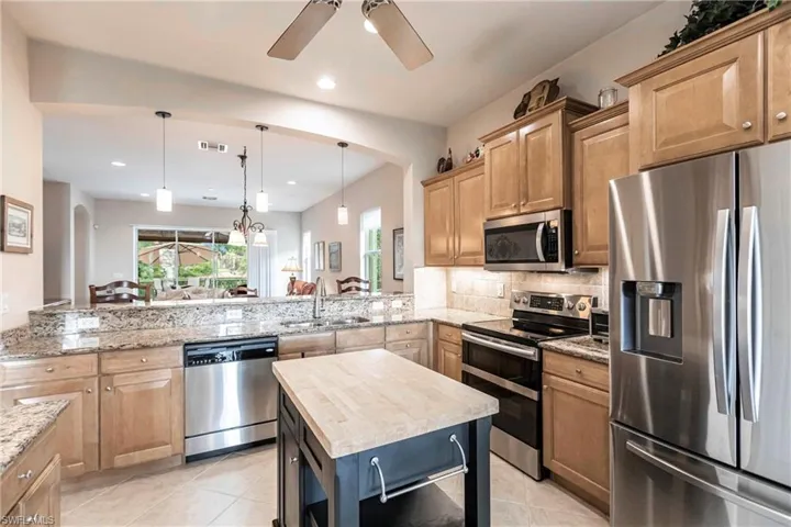 Kitchen featuring appliances with stainless steel finishes, light stone counters, hanging light fixtures, light tile patterned floors, and recessed lighting