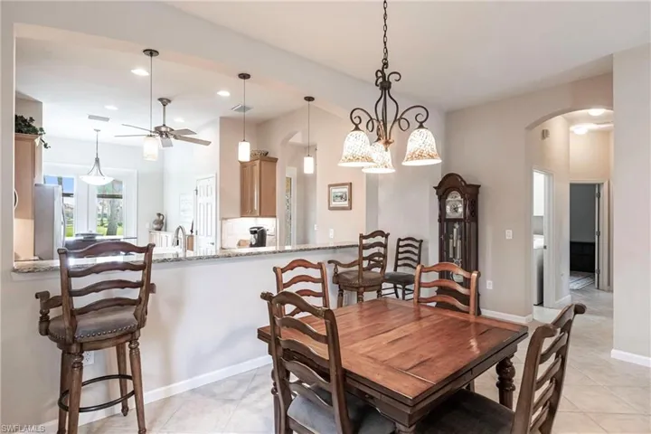 Dining space featuring recessed lighting, light tile patterned flooring, a chandelier, arched walkways, and a ceiling fan