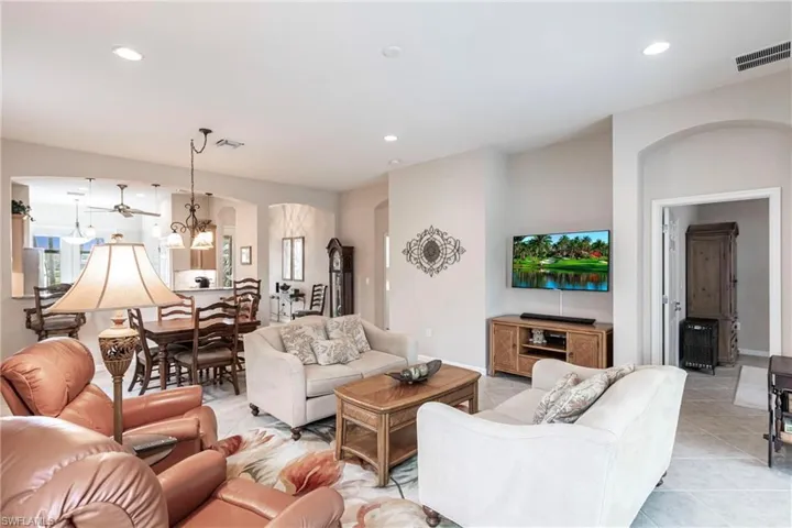 Living area with arched walkways, light tile patterned floors, and recessed lighting