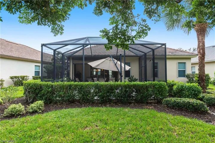 Rear view of house featuring stucco siding, a lanai, a lawn, and a sunroom