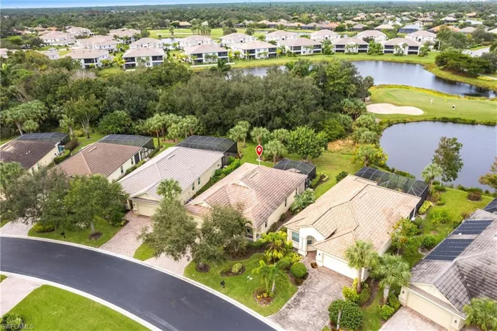 Aerial view of residential area featuring a nearby body of water and a golf course