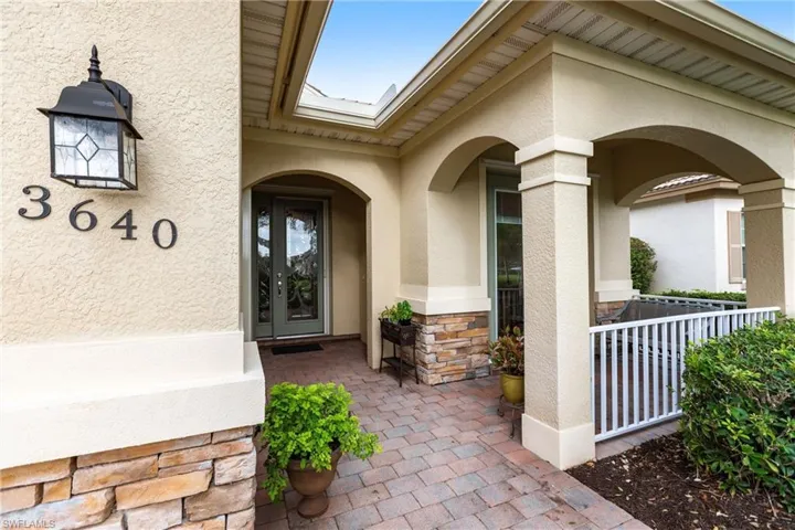 Doorway to property featuring stone siding, stucco siding, and a porch