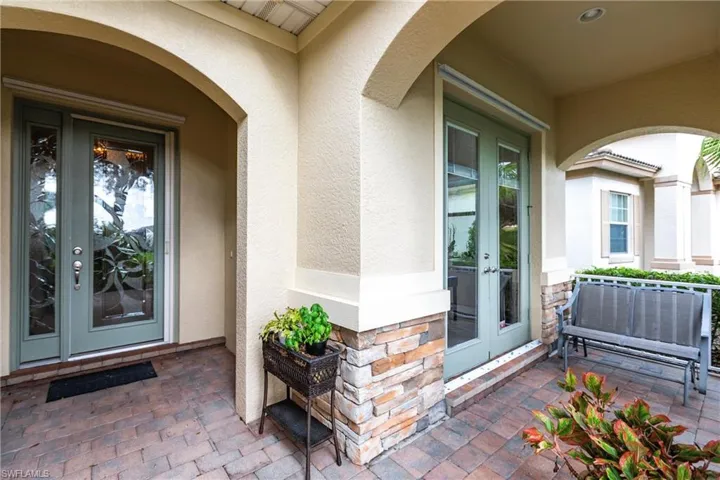 Doorway to property with french doors, stucco siding, and covered porch