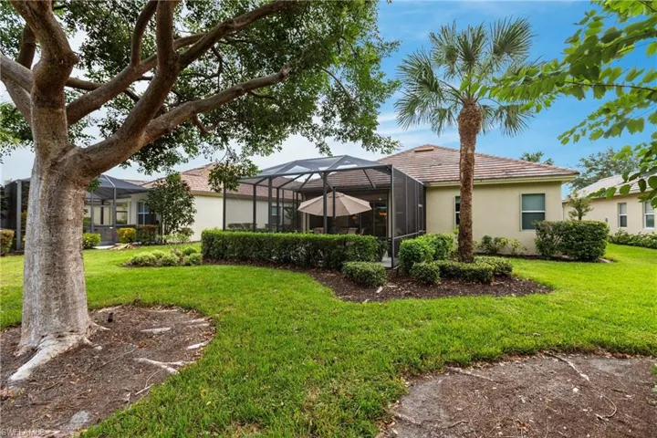 Rear view of house featuring a lanai, a lawn, a sunroom, and stucco siding