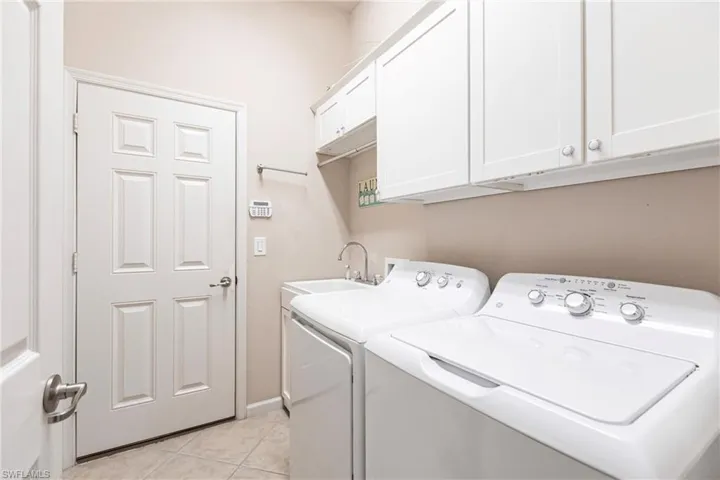 Laundry area featuring washer and clothes dryer, cabinet space, and light tile patterned floors