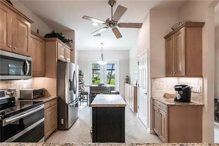 Kitchen with backsplash, appliances with stainless steel finishes, a kitchen island, and brown cabinets