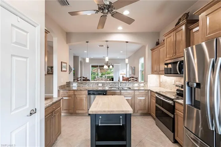 Kitchen featuring appliances with stainless steel finishes, wooden counters, decorative light fixtures, a peninsula, and recessed lighting