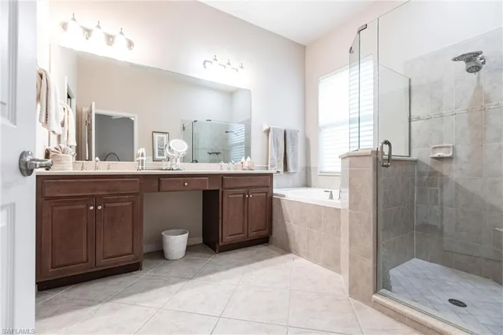 Full bath with a shower stall, double vanity, light tile patterned floors, and a bath