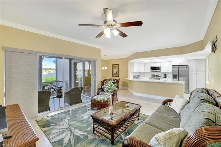 Living room with a ceiling fan, crown molding, and a water view