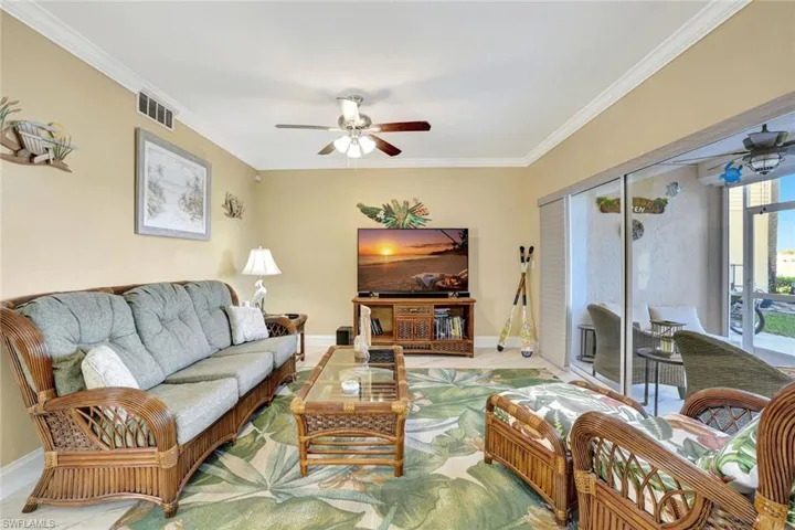 Living room featuring a ceiling fan and ornamental molding
