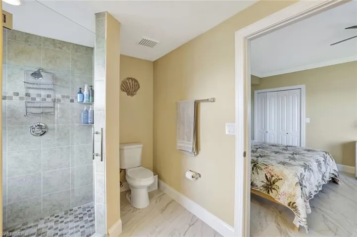 Ensuite Primary bathroom featuring marble look tile flooring, a stall shower, and crown molding
