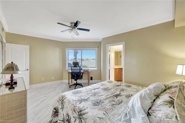 Primary bedroom with crown molding, an office area, ceiling fan, and ensuite bathroom