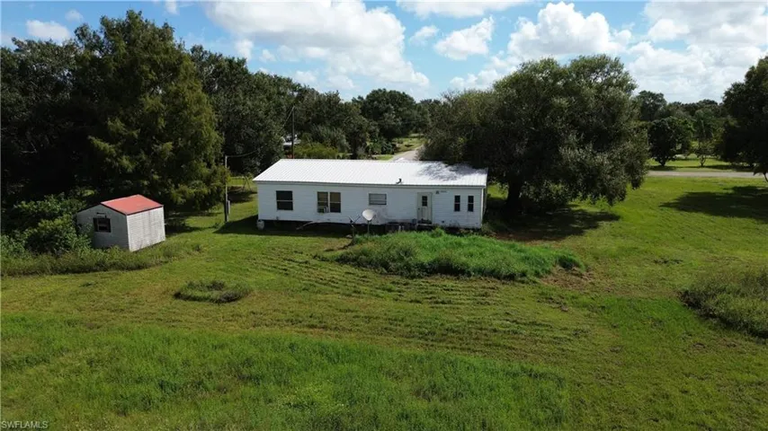 View of front facade featuring a front lawn, a shed, and a metal roof