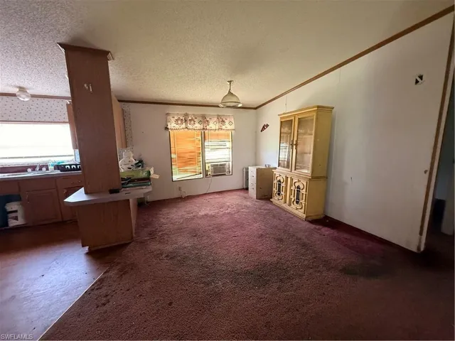 Unfurnished dining area with plenty of natural light, crown molding, dark colored carpet, and a textured ceiling