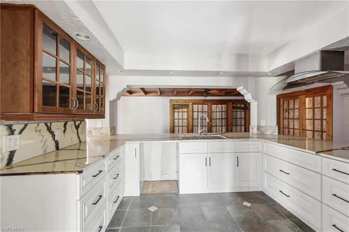 Kitchen featuring white lower cabinetry with dark hardware, light-toned countertops, and dark tile flooring