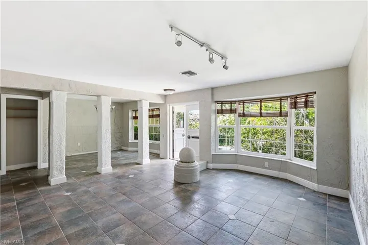 Spacious room featuring large bay windows, track lighting, ceiling-mounted light fixtures, and durable tile flooring