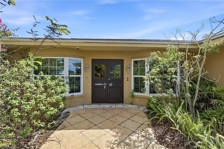 Exterior entryway featuring a double door entrance, bay windows, and a paved walkway