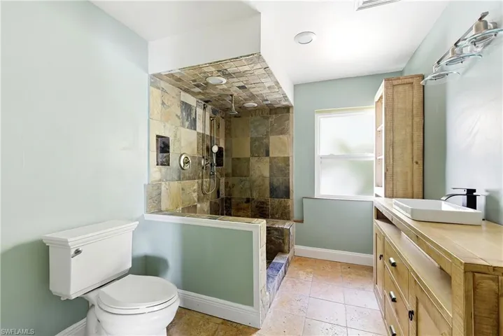 Walk-in shower with natural stone tile surround and built-in bench
