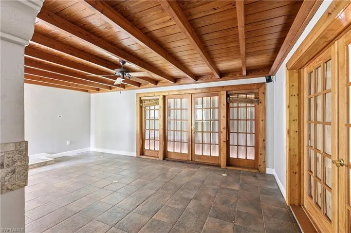 Room featuring a wood-beam ceiling, tile flooring, and multiple sets of French doors