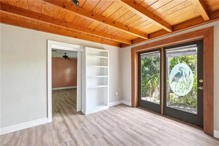 Room featuring exposed wood beam ceiling, wood-finish flooring, and built-in shelving
