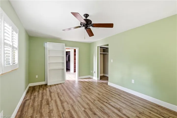 Room featuring wood-finish flooring, light green walls, and white baseboards