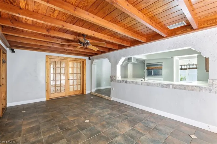 Exposed wood beam ceiling featuring recessed lighting and a ceiling fan, complemented by dark-toned floor tiles