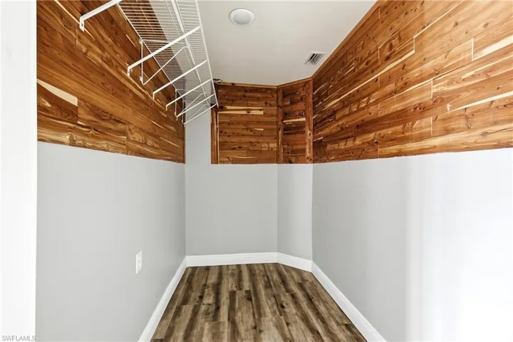 Storage area featuring wood-finish flooring, half-wall paneling, built-in shelving, and recessed lighting