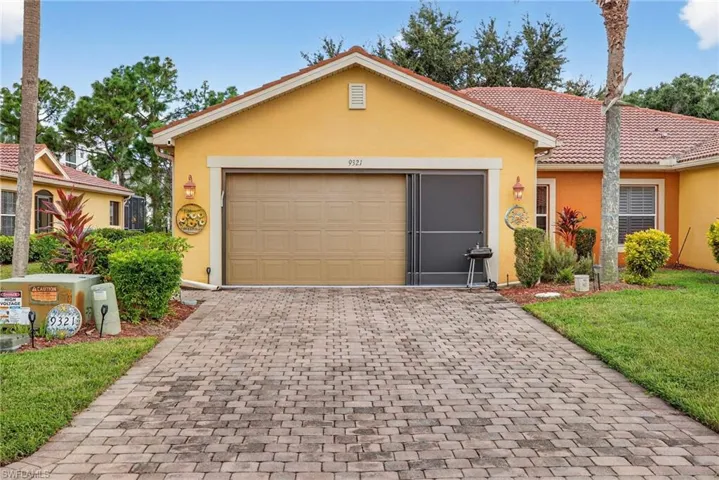 View of front of house with stucco siding, decorative driveway, a tiled roof, a front lawn, and an attached garage