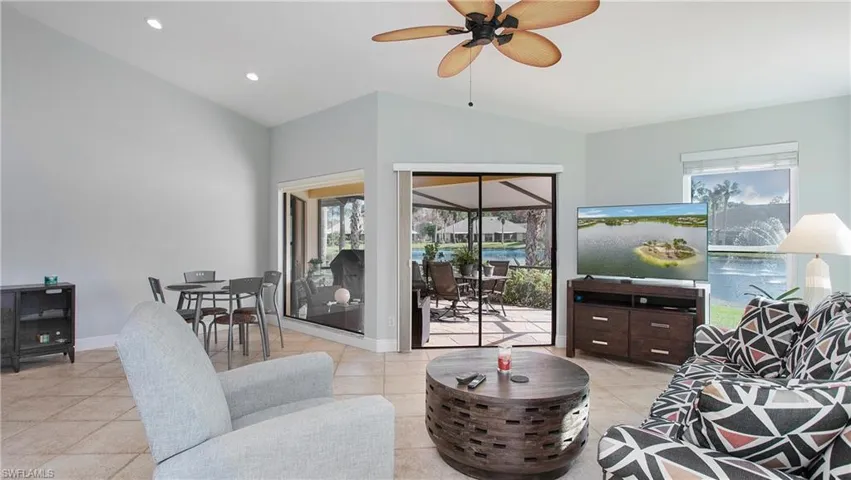 Tiled living room with ceiling fan and vaulted ceiling