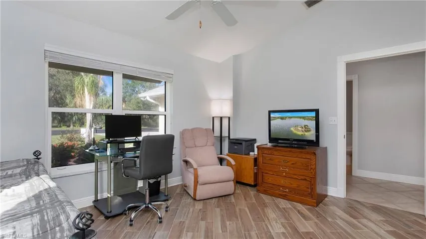 Office with light wood-style tile floors, lofted ceiling, and ceiling fan