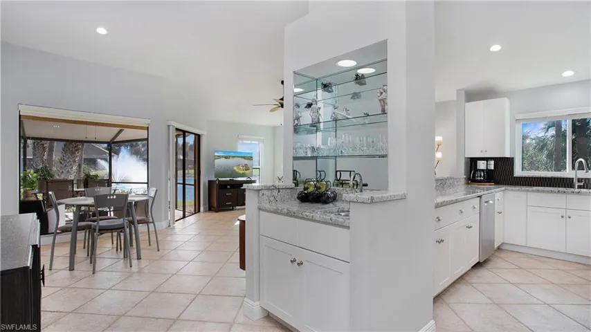 Kitchen featuring kitchen peninsula, light tile patterned floors, ceiling fan, white cabinetry, and light stone countertops
