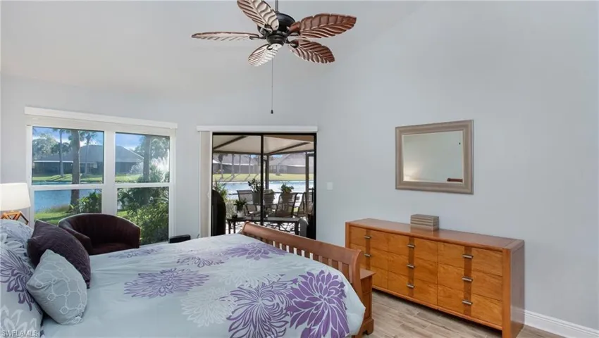 Bedroom featuring lofted ceiling, ceiling fan, access to exterior, light wood-style tile flooring, and a water view
