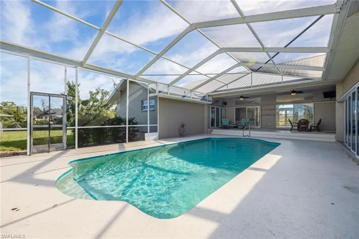 View of pool with glass enclosure, a patio area, and ceiling fan