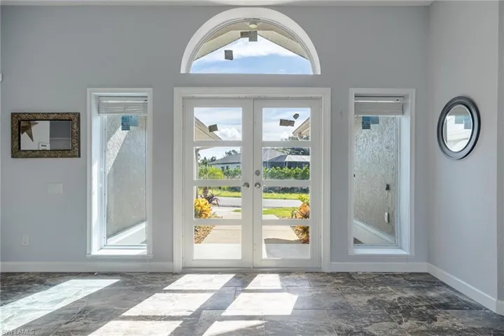 Doorway featuring french doors, dark tile patterned flooring, and plenty of natural light