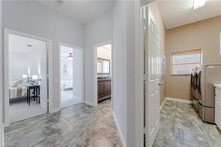Washroom with light tile patterned flooring, washing machine and dryer, and ceiling fan