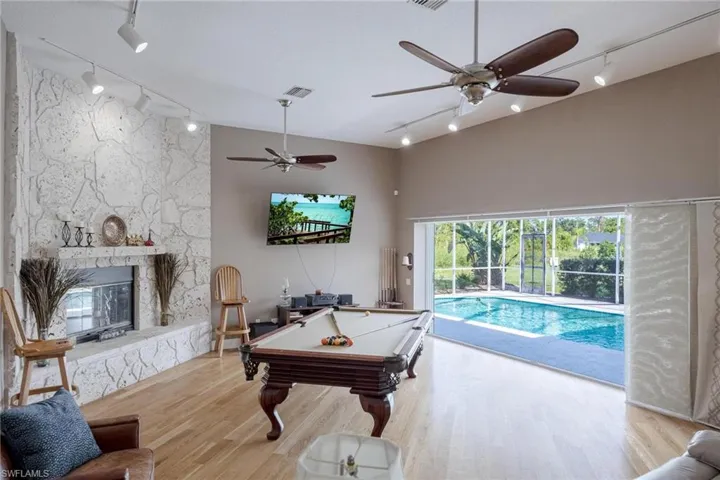 Game room with a fireplace, light hardwood / wood-style flooring, track lighting, and billiards