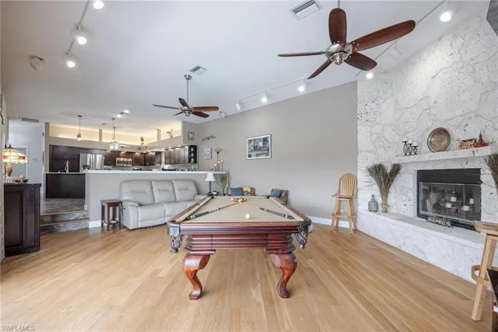 Recreation room with pool table, a fireplace, light wood-type flooring, and track lighting