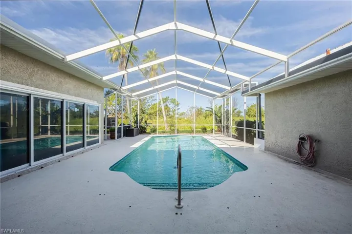 View of swimming pool with a patio area and glass enclosure