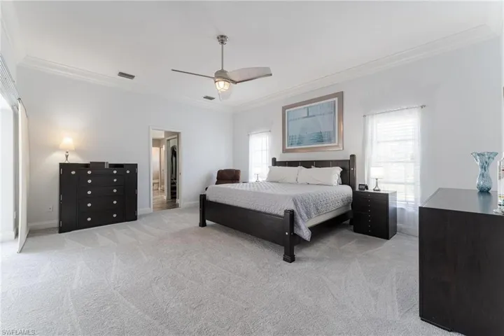 Bedroom featuring ceiling fan, carpet, and ornamental molding