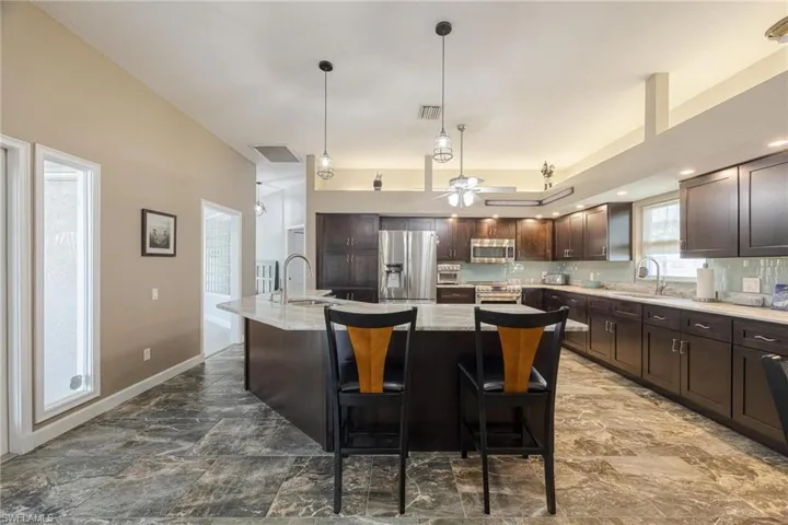 Kitchen featuring a center island with sink, stainless steel appliances, tile patterned floors, pendant lighting, and sink