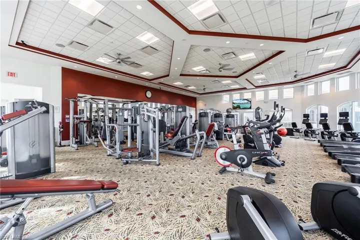 Exercise room featuring ceiling fan and a high drop ceiling
