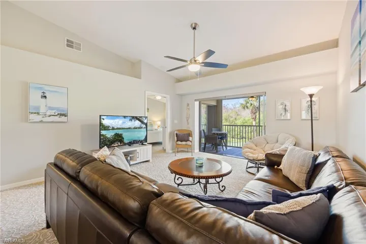 Living room with lofted ceiling, ceiling fan, and carpet flooring