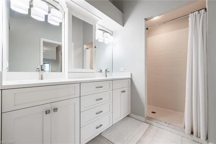 Full bathroom featuring double vanity and a stall shower