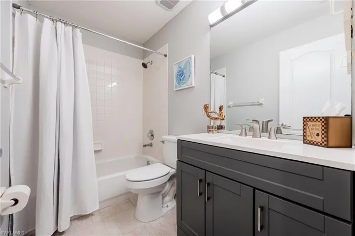 Bathroom featuring vanity, shower / bath combo with shower curtain, and light tile patterned floors