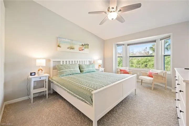 Bedroom featuring light colored carpet, vaulted ceiling, and a ceiling fan
