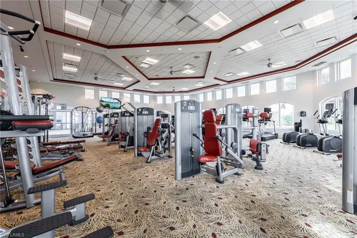 Gym with a ceiling fan and a high drop ceiling
