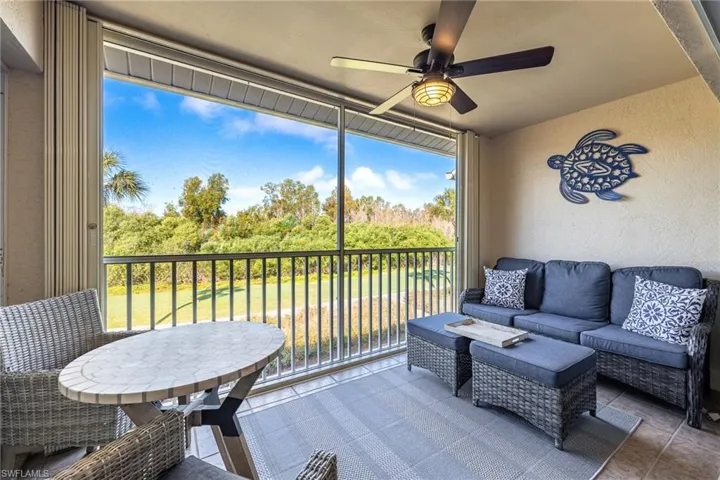 Sunroom featuring outdoor seating, ceiling fan, view of scattered trees, and a balcony