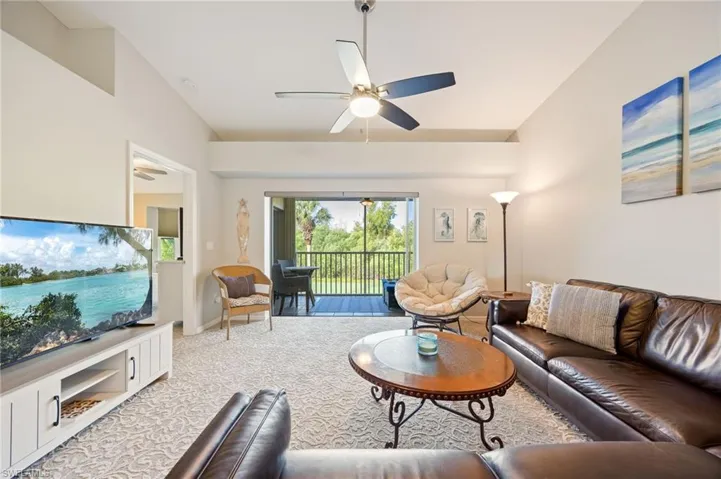 Carpeted living room featuring a ceiling fan and vaulted ceiling
