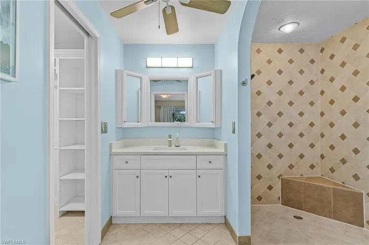 Bathroom featuring vanity, tile patterned flooring, ceiling fan, built in features, and walk in shower