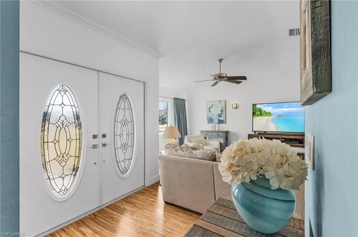 Entrance foyer featuring light hardwood / wood-style flooring, ceiling fan, and crown molding